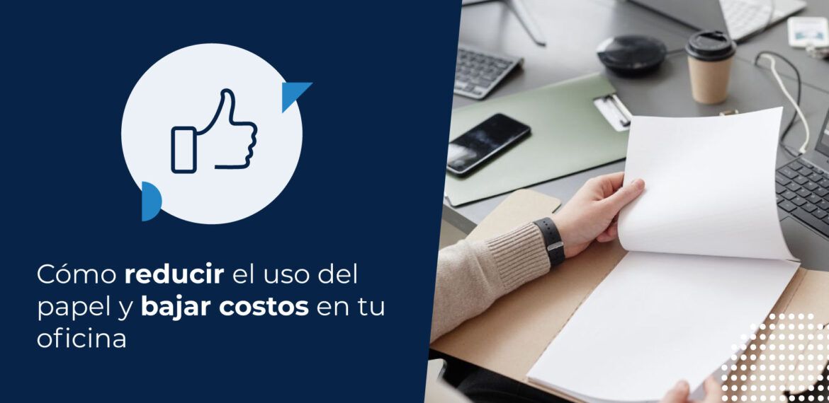 Un hombre revisando documentos de papel en una carpeta mientras trabaja en su escritorio, junto a su computadora con código en la pantalla. Esta imagen podría ilustrar cómo reducir el uso del papel en un entorno de oficina.