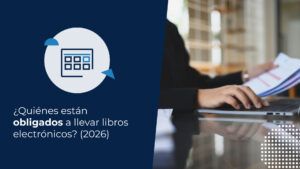 Persona en traje de oficina revisando documentos contables frente a un computador para determinar quiénes están obligados a llevar libros electrónicos.