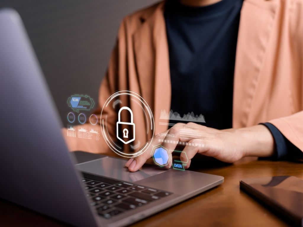 Una empresaria está usando un computador portátil del que emerge el dibujo de un candado simbolizando la seguridad que representa saber cómo transferir un certificado digital sin errores.