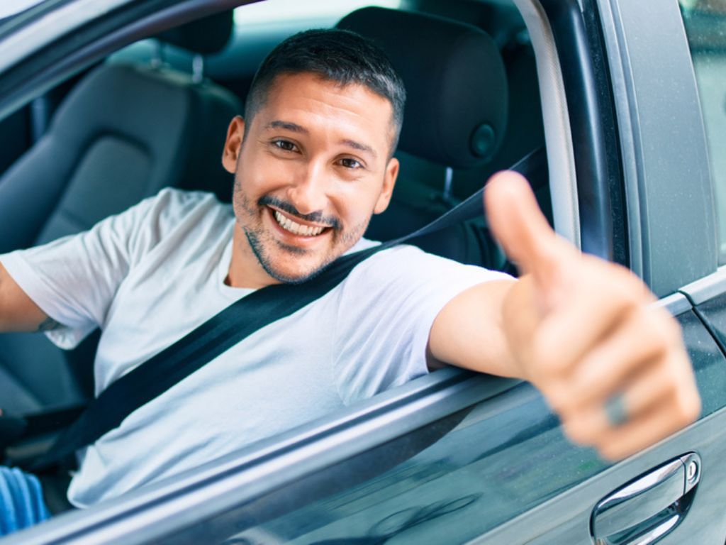 Un hombre conduce un vehículo y hace un gesto de aprobación al descubrir cómo obtener el permiso de circulación 2024.