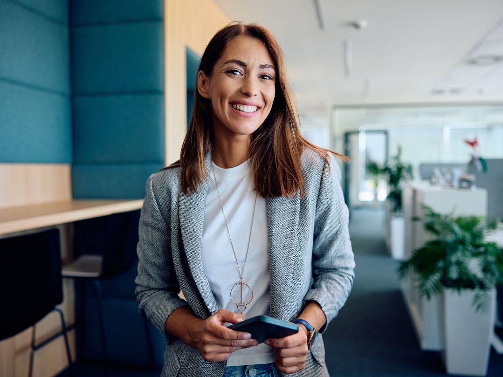 Mujer satisfecha gracias a los beneficios de la firma electrónica, que le permiten realizar una buena gestión de recursos humanos.