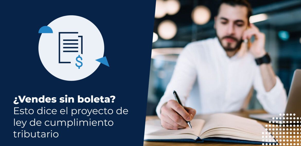 Hombre barbudo con camisa blanca escribiendo en un cuaderno con un lápiz, mientras habla por teléfono y tiene una computadora al lado, en un entorno de oficina o cafetería. Está buscando información sobre el proyecto de ley de cumplimiento tributario.