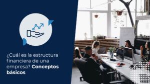 Cuatro profesionales trabajando juntos en un espacio de oficina moderno y luminoso con grandes ventanas, utilizando computadores y discutiendo. Este escenario representa una reunión de equipo en un entorno de negocios, relevante para la estructura financiera de una empresa.