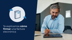 Persona firmando un documento electrónico desde un dispositivo digital mientras trabaja frente a un computador, ejemplo de cómo firmar una factura electrónica.